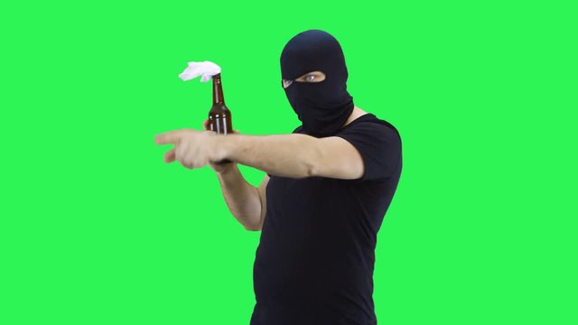A man in a black mask holds in his hand a bottle with a prosperous mixture, points to the bottle.Balaclava.Green screen background.