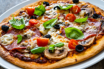Pizza with pepperoni gorgonzola and champignons on wooden table
