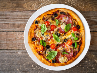 Pizza with pepperoni gorgonzola and champignons on wooden table
