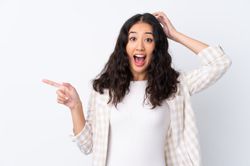 Mixed race woman over isolated white background surprised and pointing finger to the side