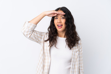 Naklejka premium Mixed race woman over isolated white background looking far away with hand to look something