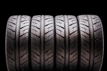 four sports tires for the summer season on a black background, isolate. for passenger cars , tuning and spare parts