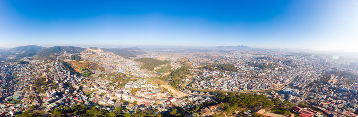 Aerial view of Da Lat city beautiful tourism destination in central highlands Vietnam. Clear blue sky. Urban development texture, green parks and city lake.