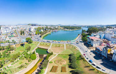 Aerial view of Da Lat city beautiful tourism destination in central highlands Vietnam. Clear blue sky. Urban development texture, green parks and city lake.