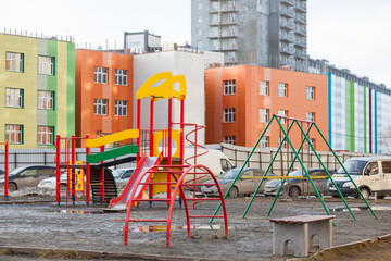 An empty children's playground painted in different colors in the courtyard of the kindergarten in the city landscape in the mode of self-isolation and quarantine.
