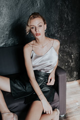 Fototapeta na wymiar portrait of a beautiful fashionable woman on a black office sofa