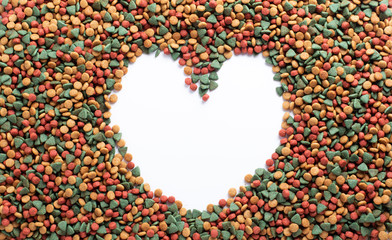 Above or Top view. Colourful Dried dog food with a shape of heart on white background. Grain animal pet food banner background with copy space shape of heart for text design.