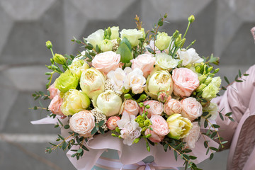 Big flowers arrangement in a hat box was created by a florist for a wedding gift. White Freesia , 
eustoma flowers, roses and eucalyptus in a bouquet. Woman florist making a flowers bouquet