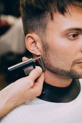 Portrait  man being trimmed with professional electric clipper machine in barbershop.Male beauty treatment concept. guy getting new haircut in barber salon