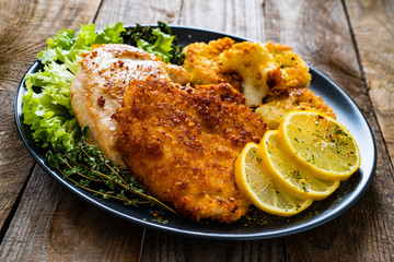 Pork chops with fried cauliflower and vegetable salad on wooden background