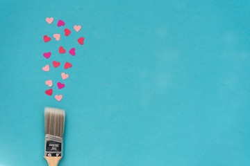 paint brush with colorful hearts blue background with copyspace