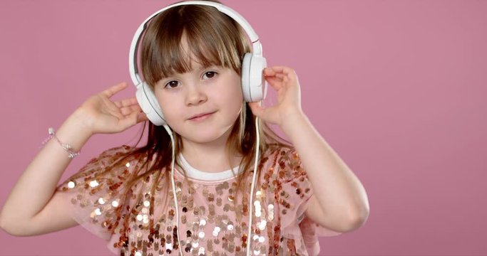 Cute little girl posing and dancing with headphones while listen to the music