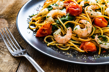 Spaghetti with prawns and vegetables on wooden background

