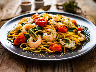 Spaghetti with prawns and vegetables on wooden background
