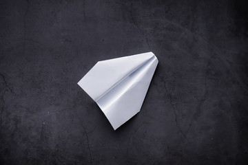 Paper airplane on the table. Origami model on a dark background. Concept. Creative waste of time.