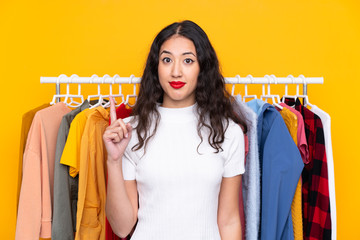 Mixed race woman in a clothing store pointing with the index finger a great idea