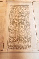 Wall inscription detail beside stone statue of the Abraham Lincoln at Memorial building.