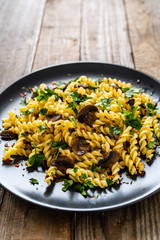 Fusilli with chmpignons on wooden table
