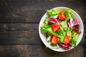 Healthy salad, leaves mix salad (mix micro greens, cucumber, tomato, onion, other ingredients) keto or paleo diet. food background. copy space 