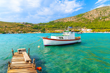 Wooden pier and colourful Greek fishing boat on turquoise sea in Posidonio bay, Samos island, Greece