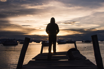 Silueta de persona de espaldas mirando el atardecer junto al mar