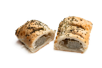 Sausage meat in puff pastry topped with herbs isolated on white