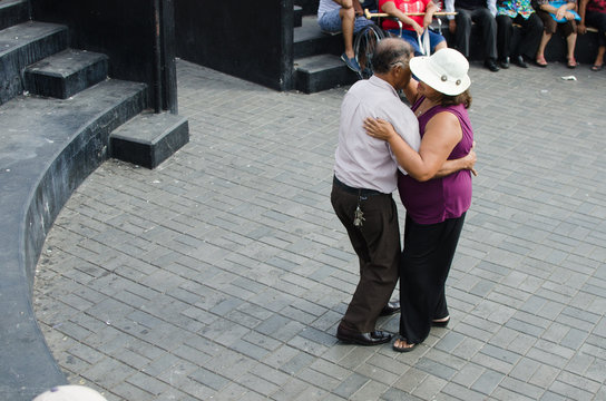 Dos personas mayores bailando juntos en una plaza de Lima