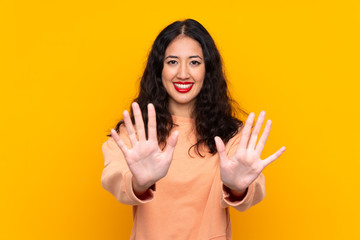 Spanish Chinese woman over isolated yellow background counting ten with fingers