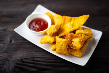 Deep fired Chinese Thai style wonton with minced pork and sweet and sour sauce in ceramic dish.