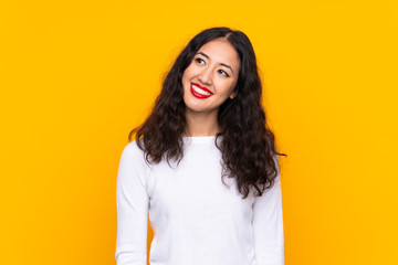Mixed race woman over isolated yellow background laughing and looking up