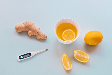 Cup of tea with Lemon and Ginger and termometer on blue background. Home remedies concept. Top view