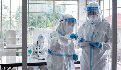 Scientists and microbiologists with PPE suit and face mask in lab calculate chemical formula to create vaccine or medicine for coronavirus infection. Covid-19, laboratory, and vaccine concept.