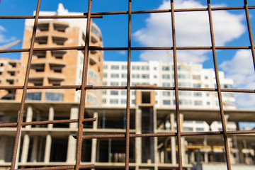 construction building unfocused silhouette shape behind rusty sharp fence foreground