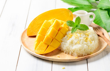Ripe mango and sticky rice with coconut milk on white wood background,
