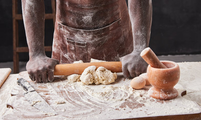Dark skin baker man kneads Dough in the kitchen. Pastry chef prepares yeast dough for pizza pasta.