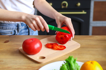 Slicing red pepper on salad, girl prepares salad at home in the kitchen