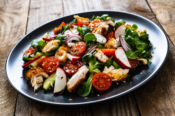 Caesar salad - fried chicken breast and vegetables on wooden table
