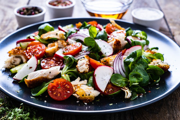 Caesar salad - fried chicken breast and vegetables on wooden table
