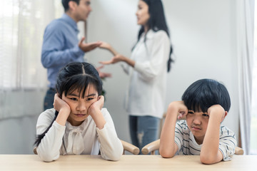 Fototapeta na wymiar Two young children feeling sad and boring due to parents fighting at home. Older sister feels disappointed and sibling brother crying on father and mother aggressive trouble. Unhappy problem in family