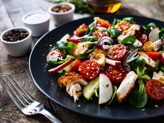 Caesar salad - fried chicken breast and vegetables on wooden table
