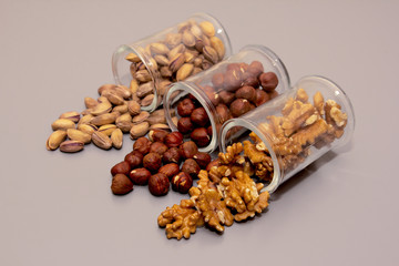 different nuts - hazelnut, walnut and pistachio nut. in glass box on light background