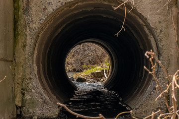 Concrete pipe for meltwater runoff. Through the tube you can see nature at the far end