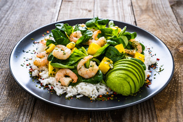 Prawns with rice and vegetables on wooden table
