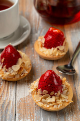 Small tartlet with cream and a whole strawberry, glazed and golden for decoration
