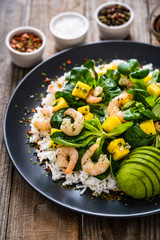 Prawns with rice and vegetables on wooden table
