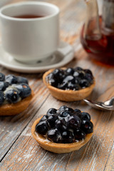 Close up of rustic homemade tartlets with custard and blueberry