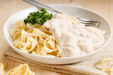 Italian pasta fettuccine in creamy sauce on wooden table
