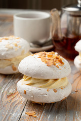 Meringue stuffed with whipped cream custard and almond flakes, served with a cup of tea on vintage-style table
