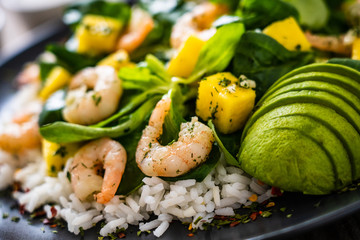 Prawns with rice and vegetables on wooden table
