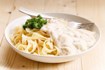 Italian pasta fettuccine in creamy sauce on wooden table